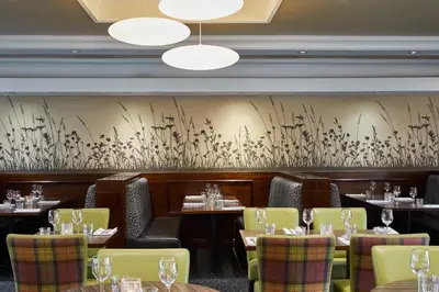 a restaurant with tables and chairs and a wall at Leonardo Inn Glasgow West End in Glasgow
