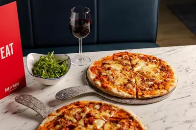 two pizzas sitting on a table with a glass of wine at Leonardo Inn Glasgow West End in Glasgow