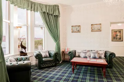a living room with two couches and a table at Muthu Queens Hotel, Oban in Oban