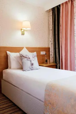 a bedroom with a white bed with a lamp on it at Muthu Queens Hotel, Oban in Oban