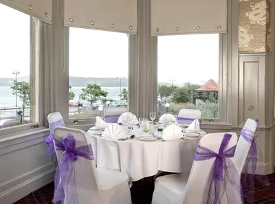 a dining room with a white table with purple bows at Argyll Hotel in Dunoon