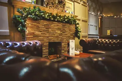 a living room with a fireplace and leather couches at Argyll Hotel in Dunoon