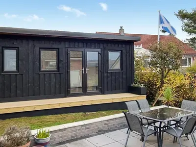 a black tiny house with a table and chairs at Glencairn Rd in Langbank