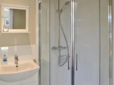 a white bathroom with a shower and a sink at Glencairn Rd in Langbank