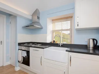 a white kitchen with a sink and a stove at Nettlebush Cottage-Uk5629 in Drummelzier