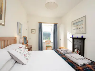 a bedroom with a white bed and a fireplace at Nettlebush Cottage-Uk5629 in Drummelzier