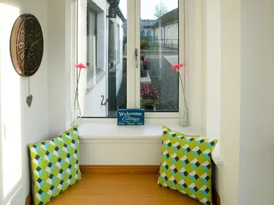 a window with a clock and two pillows in a room at Rossie Cottage in Auchterarder
