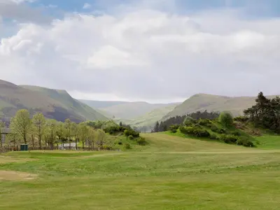 a green field with mountains in the background at Rossie Cottage in Auchterarder