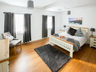 a bedroom with a bed and a couch and a chair at Rossie Cottage in Auchterarder