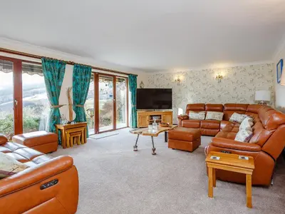 a living room with leather furniture and a flat screen tv at Ard Taigh in Stron-fearnan