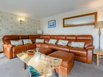 a living room with a leather couch and a table at Ard Taigh in Stron-fearnan