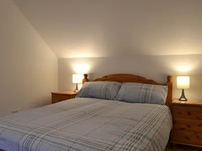 a bedroom with a bed with two lamps on night stands at Riverside in Kilmelford