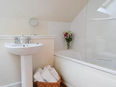 a white bathroom with a sink and a bath tub at Riverside in Kilmelford