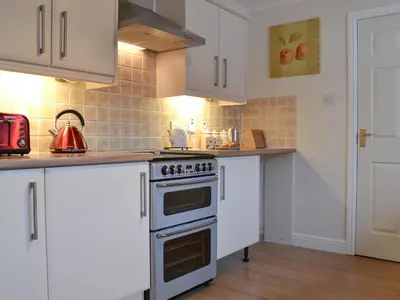 a kitchen with white cabinets and a stove top oven at Riverside in Kilmelford