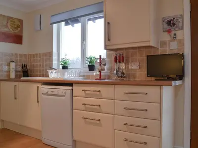 a kitchen with white cabinets and a tv on the counter at Riverside in Kilmelford