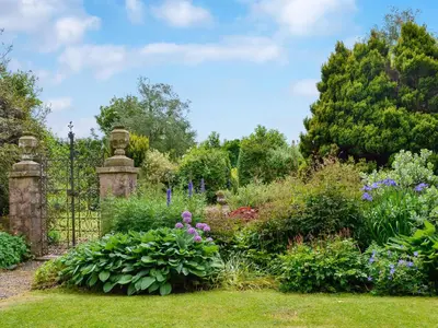 a garden with a gate and a bunch of flowers at The Old Stables in Sorn