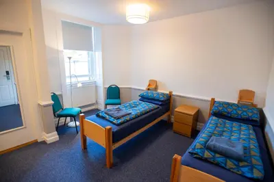 a room with two beds and chairs and a window at Glasgow Youth Hostel in Glasgow