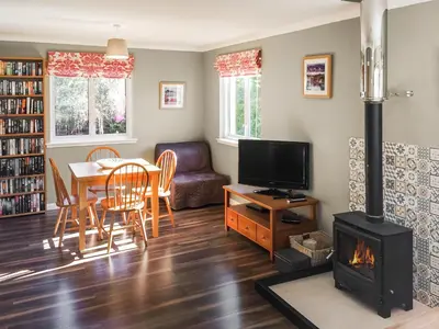 a living room with a table and a fireplace at Achnaha in Ardentinny
