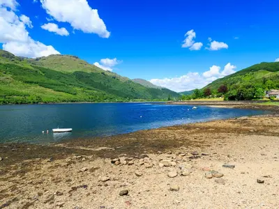 a body of water with a boat on the shore at Achnaha in Ardentinny
