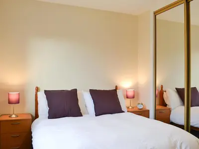 a bedroom with a white bed with two lamps and a mirror at Achnaha in Ardentinny