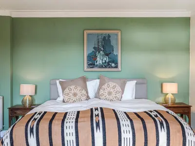a bedroom with a large bed with two lamps at Strathcashel Cottage in Rowardennan
