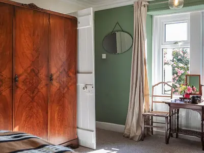 a bedroom with a large wooden cabinet and a table at Strathcashel Cottage in Rowardennan
