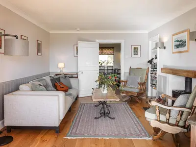 a living room with a couch and a table at Strathcashel Cottage in Rowardennan