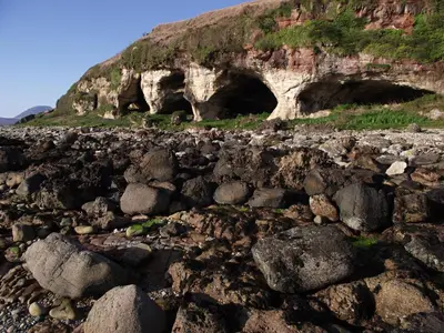 a rocky field with two tunnels in the side of a mountain at Lochranza Youth Hostel in Lochranza
