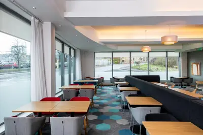 a restaurant with wooden tables and chairs and windows at Holiday Inn Express Hamilton by IHG in Hamilton