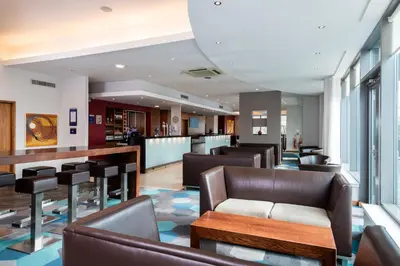 a lobby with leather chairs and a bar at Holiday Inn Express Hamilton by IHG in Hamilton