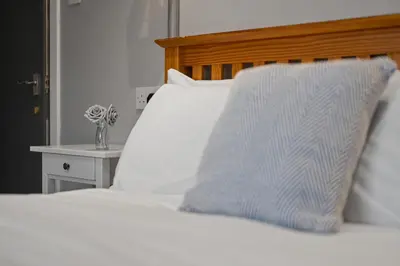 a white bed with a blue pillow on it at Queensferry Guest house in Rosyth