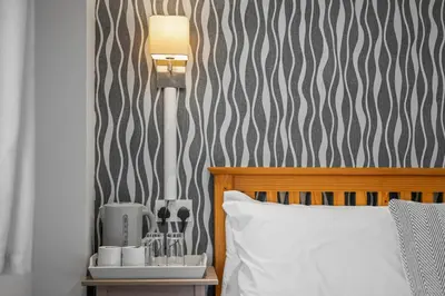 a bedroom with a bed with a lamp and a side table at Queensferry Guest house in Rosyth