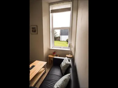 a living room with a couch and a window at Cedar Apartment in Helensburgh