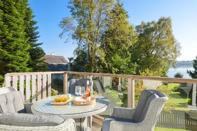 a patio with a table and chairs on a balcony at Dunbheag Cottage in Strone
