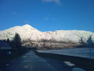 a mountain covered in snow next to a road at Inn at Ardgour in Onich