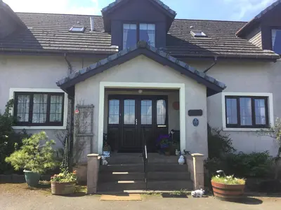 a white house with a black door and stairs at Woodcockfaulds House in Stirling