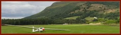 a small plane sitting on a green field with a mountain at Kirklands Hotel in Kinross