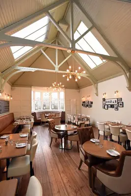 a restaurant with wooden tables and chairs and windows at Kirklands Hotel in Kinross