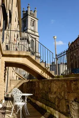 a table and chair sitting on a bridge with a clock tower at JOIVY Gorgeous Flat near The Scotland Gallery in Edinburgh