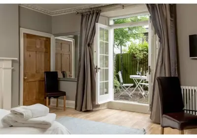 a bedroom with a bed and a sliding glass door at JOIVY Boutique Apt with Patio in New Town in Edinburgh