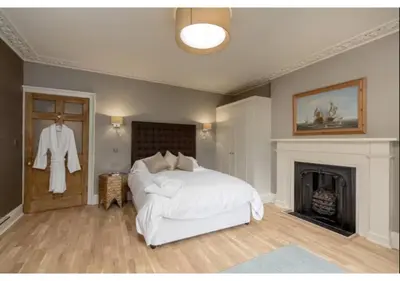 a bedroom with a white bed and a fireplace at JOIVY Boutique Apt with Patio in New Town in Edinburgh
