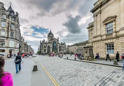a group of people walking down a street in a city at JOIVY Charming Nest for Two with Castle View in Edinburgh