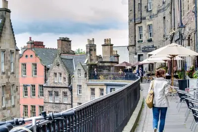 a woman walking on a bridge over a city at JOIVY Charming Nest for Two with Castle View in Edinburgh