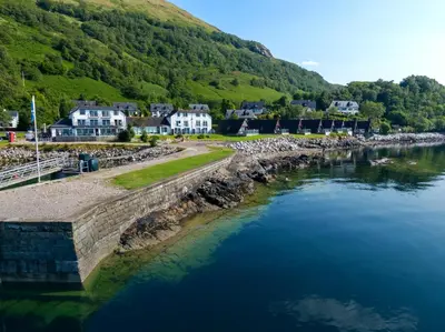 an aerial view of a river with houses and mountains at Holly Tree Hotel, Swimming Pool & Hot Tub in Glencoe