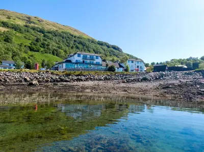 a house on the shore of a body of water at Holly Tree Hotel, Swimming Pool & Hot Tub in Glencoe