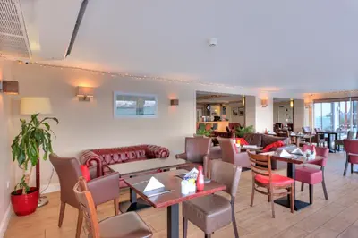 a restaurant with tables and chairs and couches at Holly Tree Hotel, Swimming Pool & Hot Tub in Glencoe