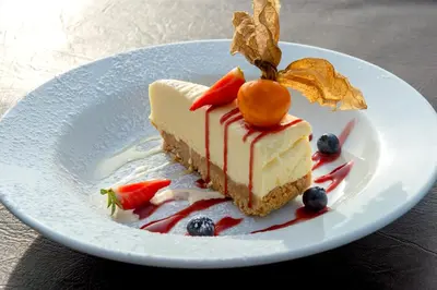 a piece of cake with fruit on a white plate at Holly Tree Hotel, Swimming Pool & Hot Tub in Glencoe