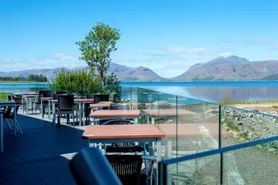 a balcony with tables and chairs and a view of a lake at Holly Tree Hotel, Swimming Pool & Hot Tub in Glencoe