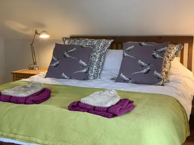 a bed with two knitted blankets and pillows on it at Charming cottage with loch and hill views nr Edinburgh in Cobbinshaw