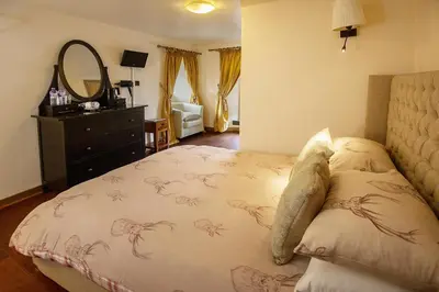 a bedroom with a bed with a dresser and a mirror at The Falls Of Dochart Inn in Killin